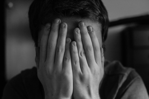 Black-and-White Photo of Grieving College Student whose Hands Cover His Face
