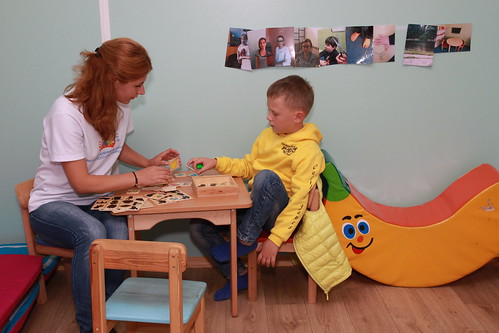 Boy with Learning Disability Using Puzzles and Games to Play with His Mentor at Small Table
