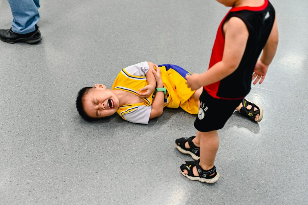 A young boy lying on a ground, crying and having a tantrum