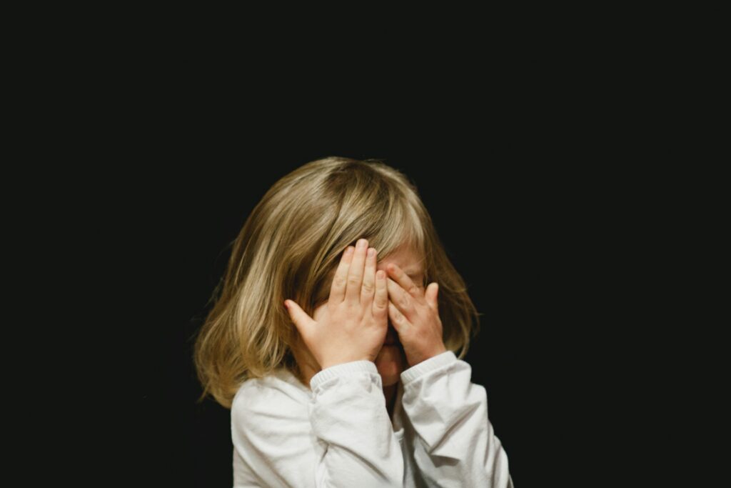 Young girl covering her face with her hands